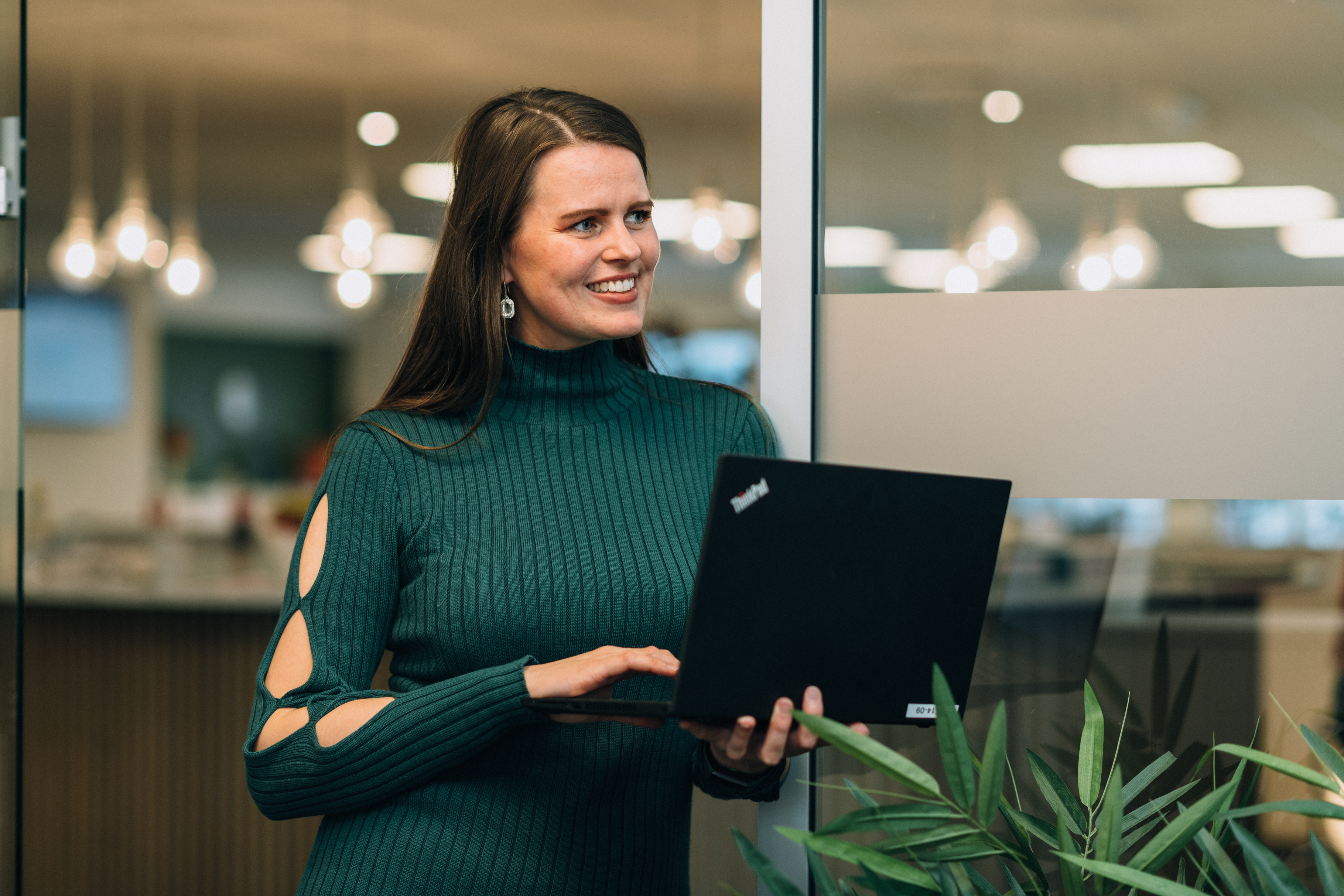 Portrett av ansatt Cecilie i en døråpning med åpen laptop i hendene
