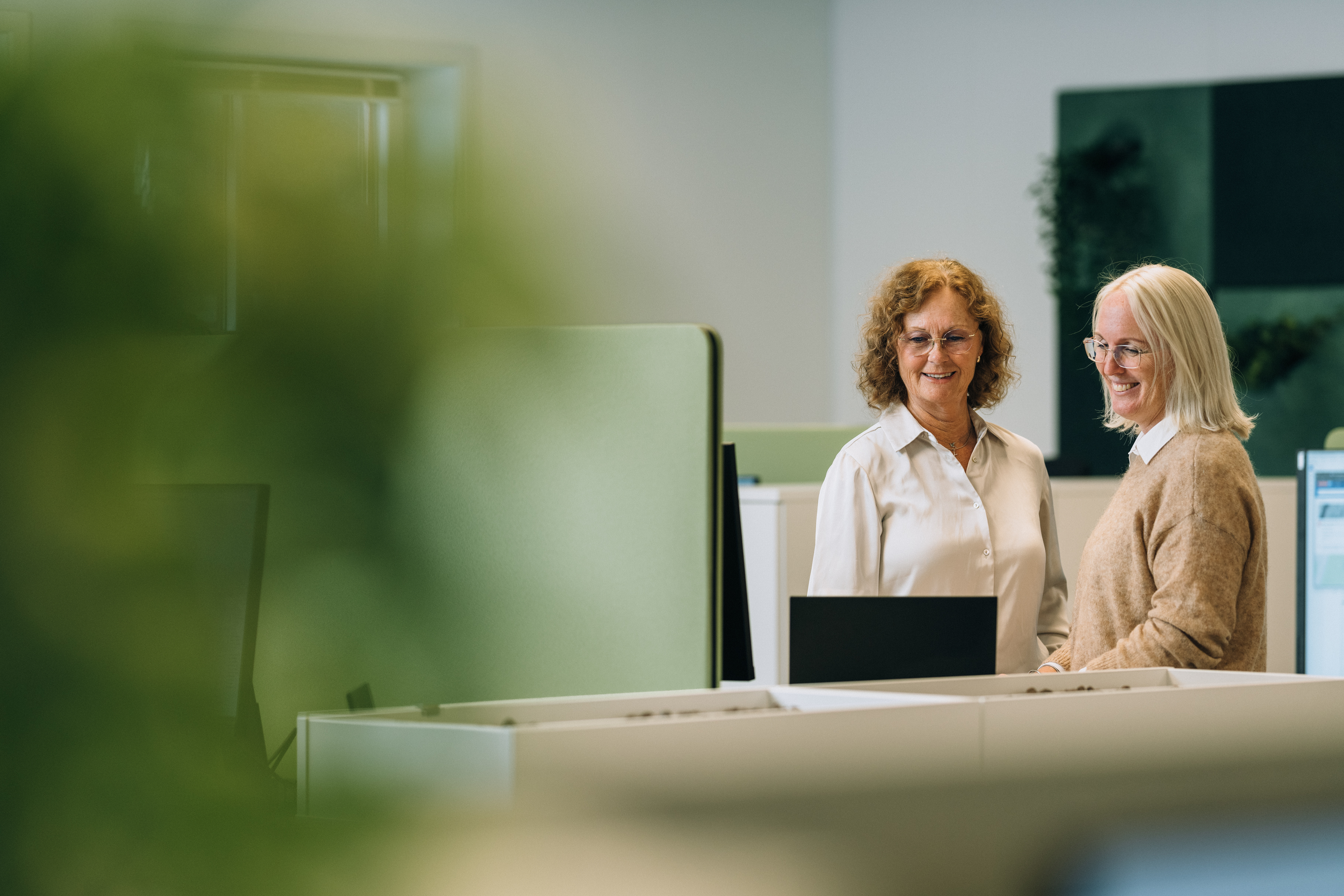 Ansatte Yvonne og Maria som ser over informasjon på pc skjerm sammen