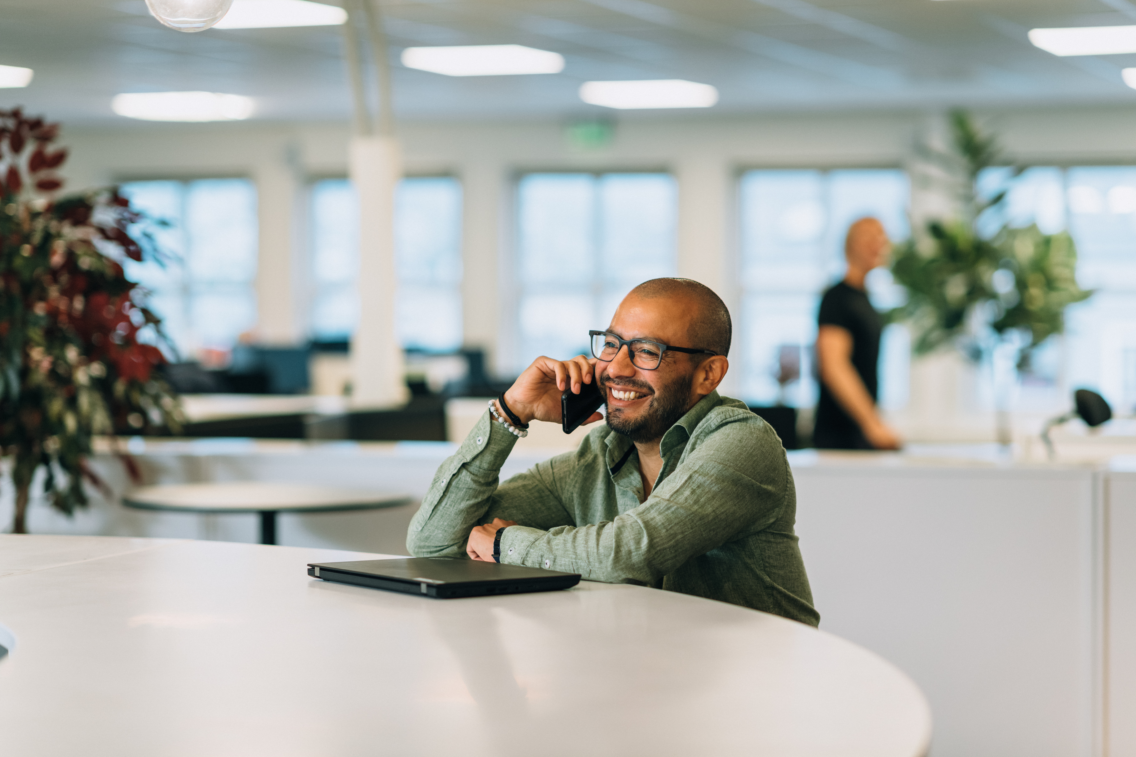 Ansatt Vegard lund tar en telefonsamtale i baren, i kontorlandskapet i bakgrunnen ser vi en uskarp mann som går forbi