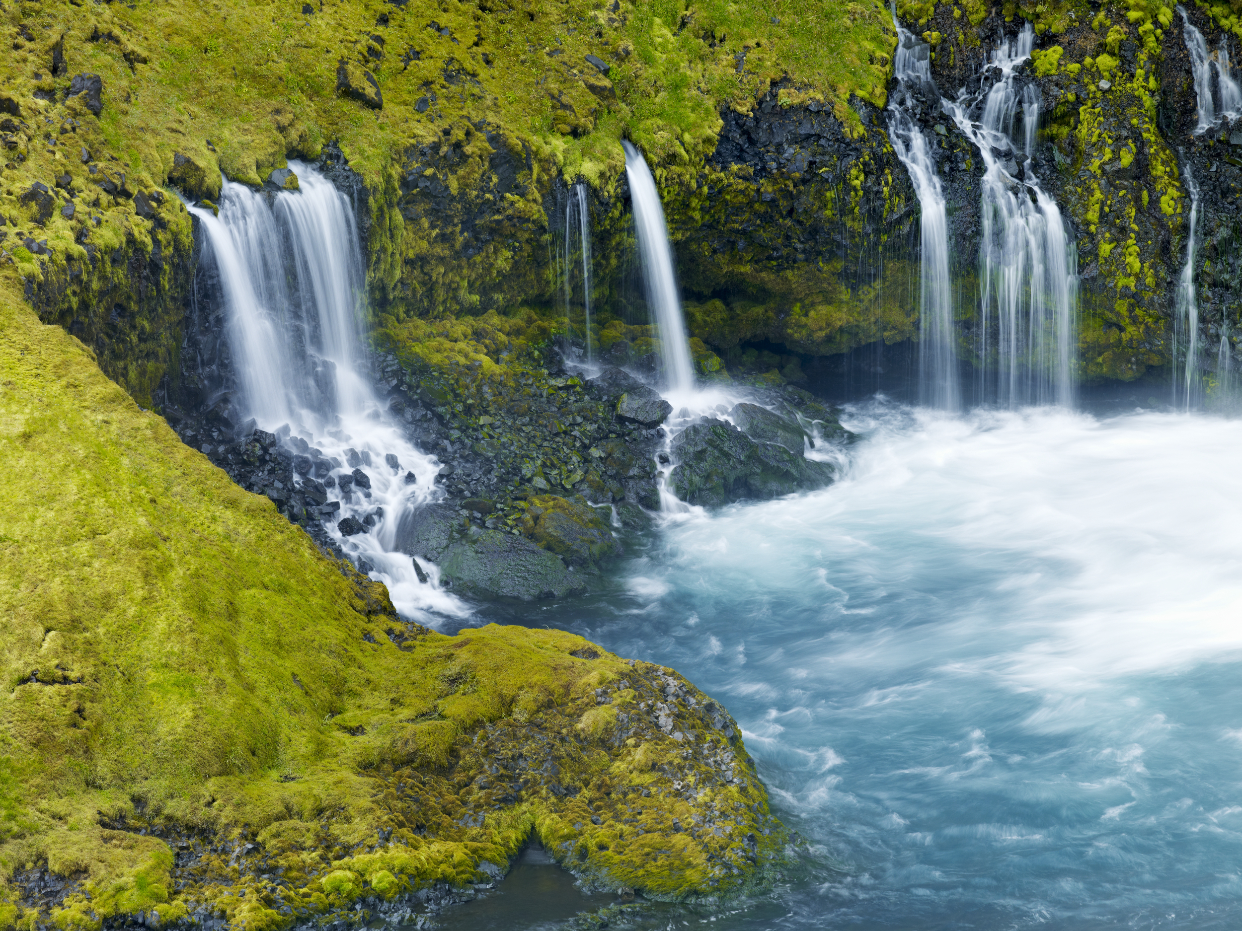 Several small waterfalls that end in a large blue pool